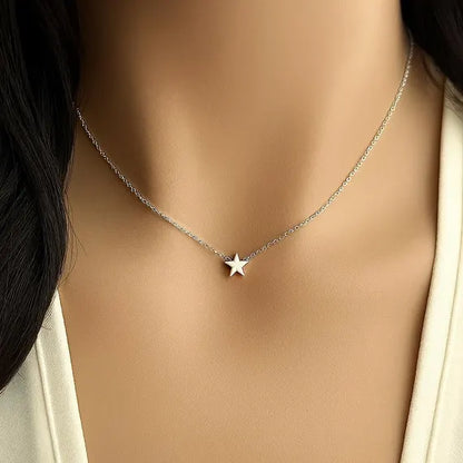 Collier fantaisie étoile en or blanc porté au cou d'une une femme vue de face.