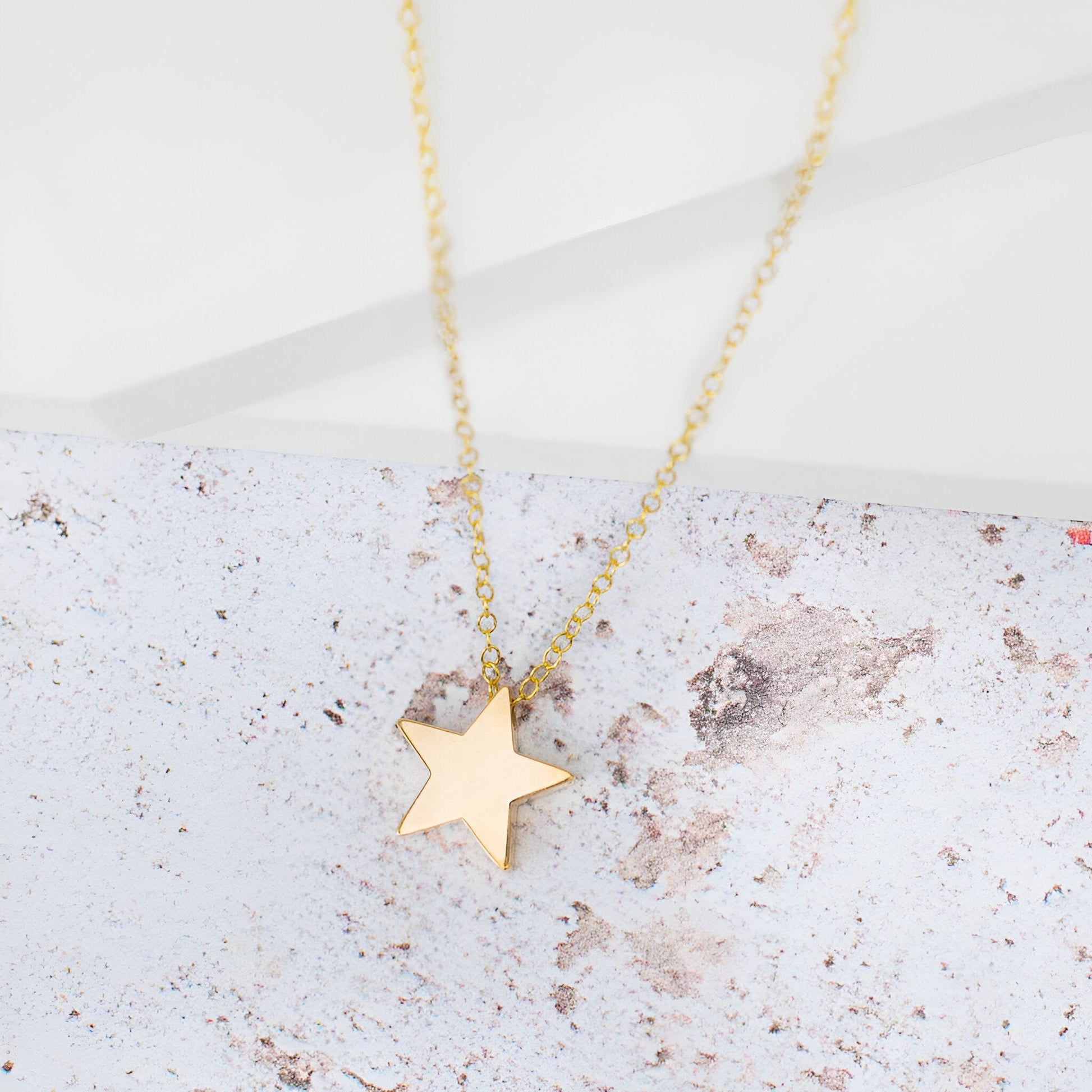 Collier fantaisie étoile en or jaune à plat.