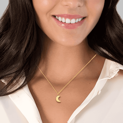 Collier fantaisie lune en or jaune porté au cou d'une femme vue de face.