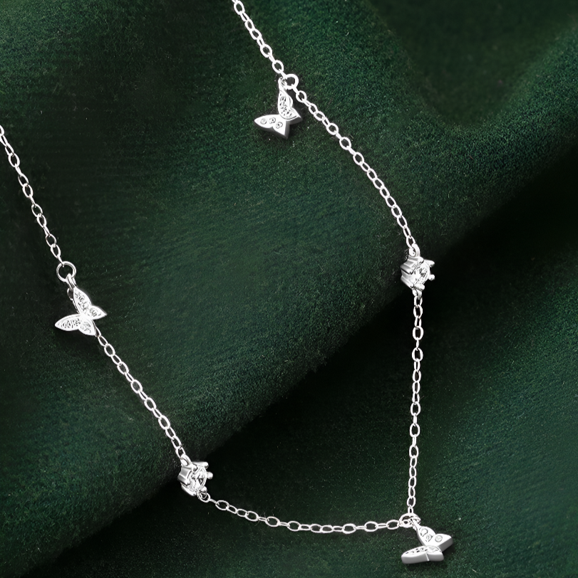 Détail du collier fantaisie papillons avec éclats de diamants de zircon sur fond vert foncé