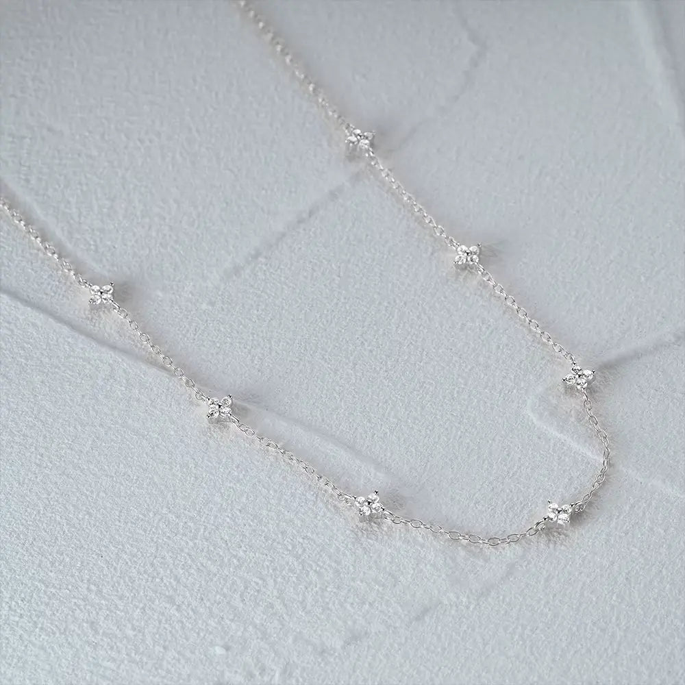 Collier fleurs chaîne forçat en argent 925 plaqué or blanc et zircons naturels à plat vue de côté.