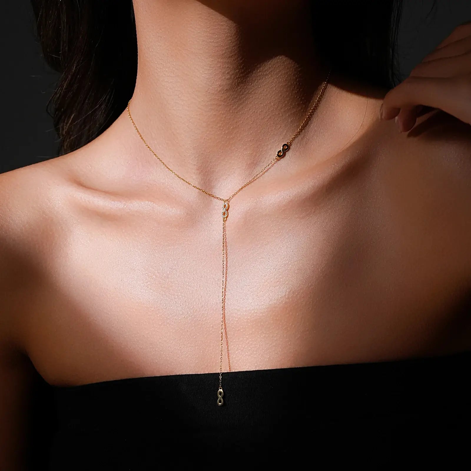 Collier long motif infini albert en argent 925 plaqué or jaune et diamants en zircon naturels porté au cou d'une femme.