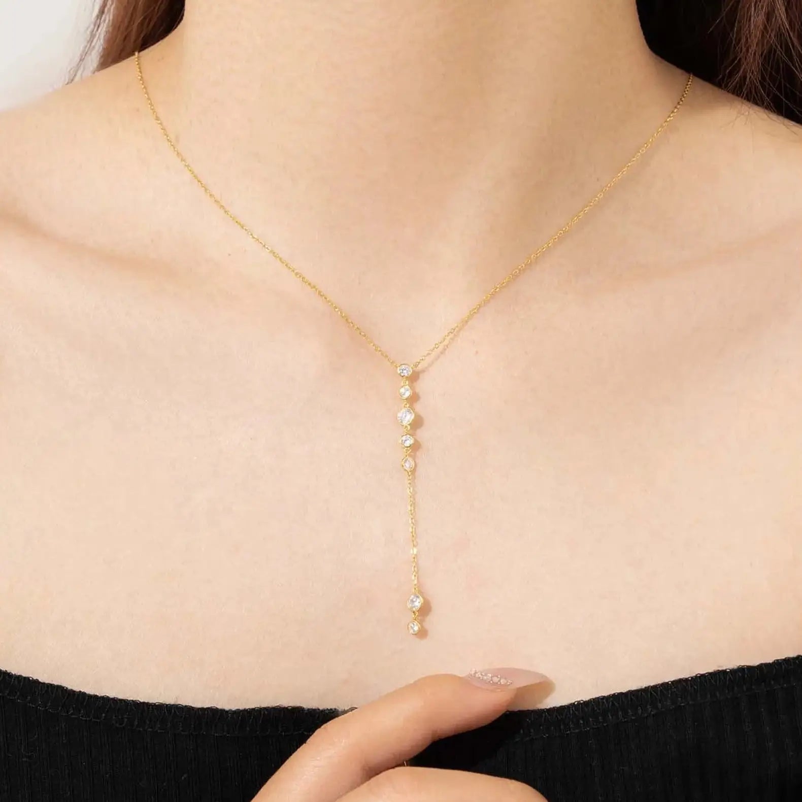 Collier long pendentif Noëvan en argent plaqué or jaune et diamants en zircon porté au cou d'une femme.