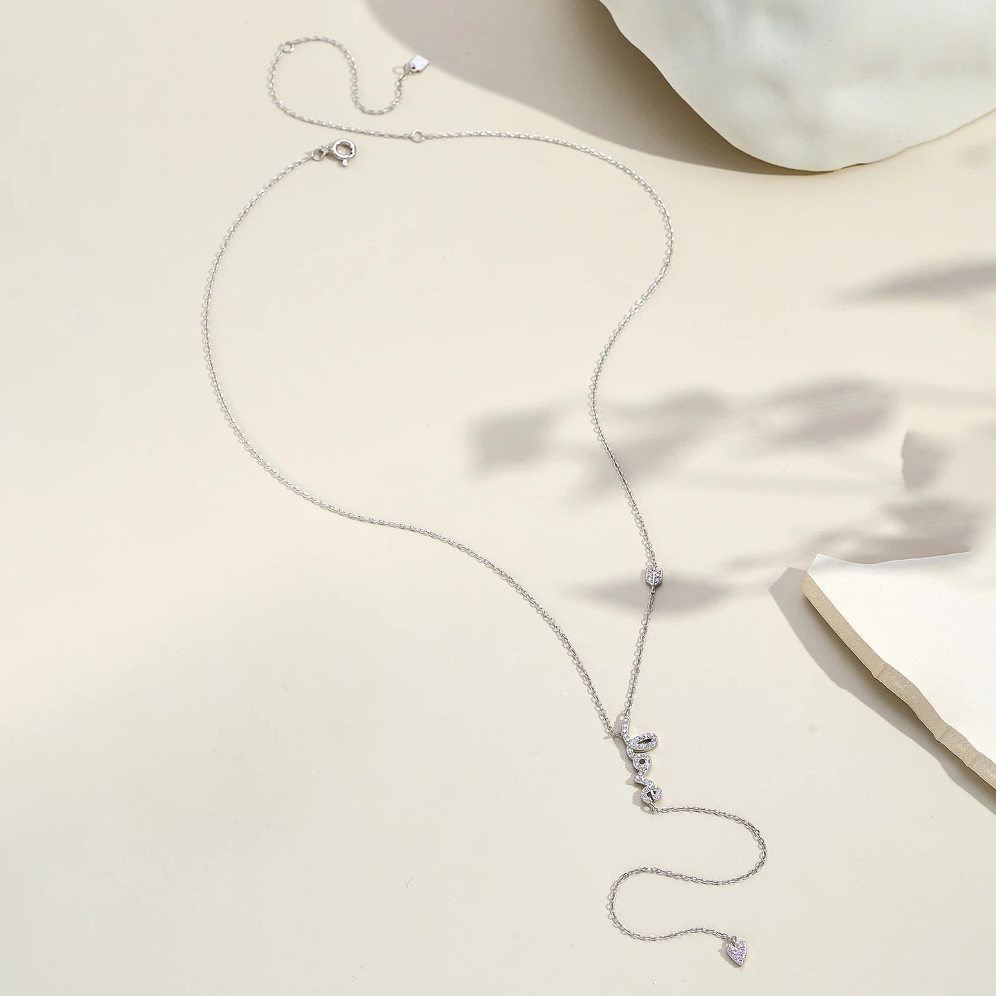 Collier love long pendentif cœur en argent 925 plaqué or blanc et diamants en zircon blancs et roses à plat vue en entier.