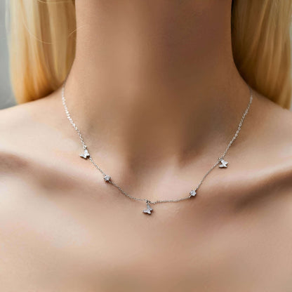 Collier maille argentée papillons en argent 925 plaqué or blanc et zircons scintillants porté au cou d'une femme vue de face.