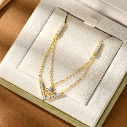 Collier multi-chaînes pendentif V en argent 925 plaqué or jaune chaleureux et diamants rangé dans son écrin vue de face.
