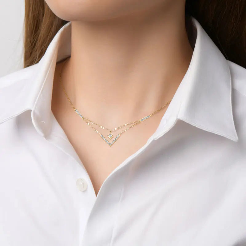 Collier multi-chaînes pendentif V en argent 925 plaqué or jaune et diamants étincelants porté au cou d'une femme vue de loin.