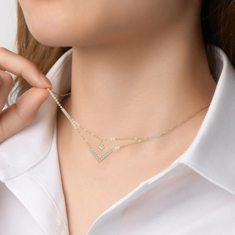 Collier multi-chaînes pendentif V en argent 925 plaqué or jaune et diamants porté au cou d'une femme vue de proche.