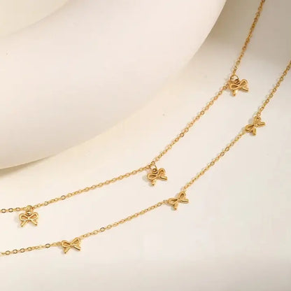 Collier nœud papillon en acier inoxydable plaqué or jaune variantes breloques et incrusté à plat.