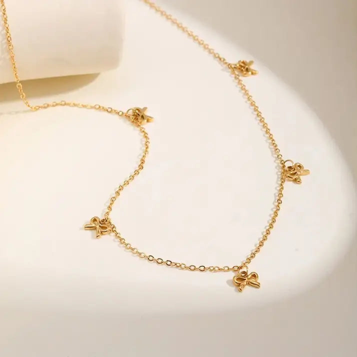 Collier nœud papillon en acier inoxydable plaqué or jaune variante breloques à plat.