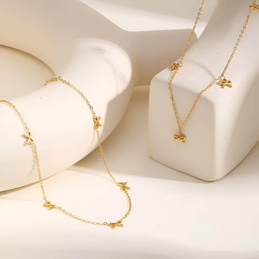 Collier nœud papillon en acier inoxydable plaqué or jaune variantes breloques et incrusté posés.