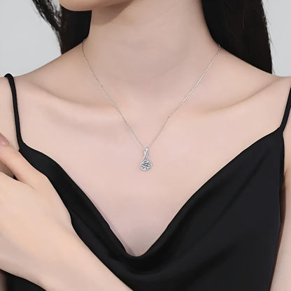 Collier pendentif goutte arqué en argent sterling 925 plaqué or blanc et moissanite solitaire sertie 4 griffes porté au cou d'une femme vue de loin.