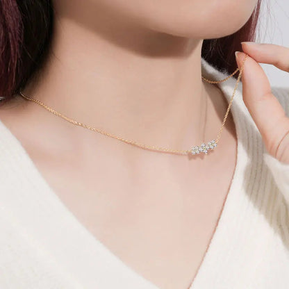 Collier pendentif en or jaune et diamants synthétiques porté au cou d'une femme vue de côté.