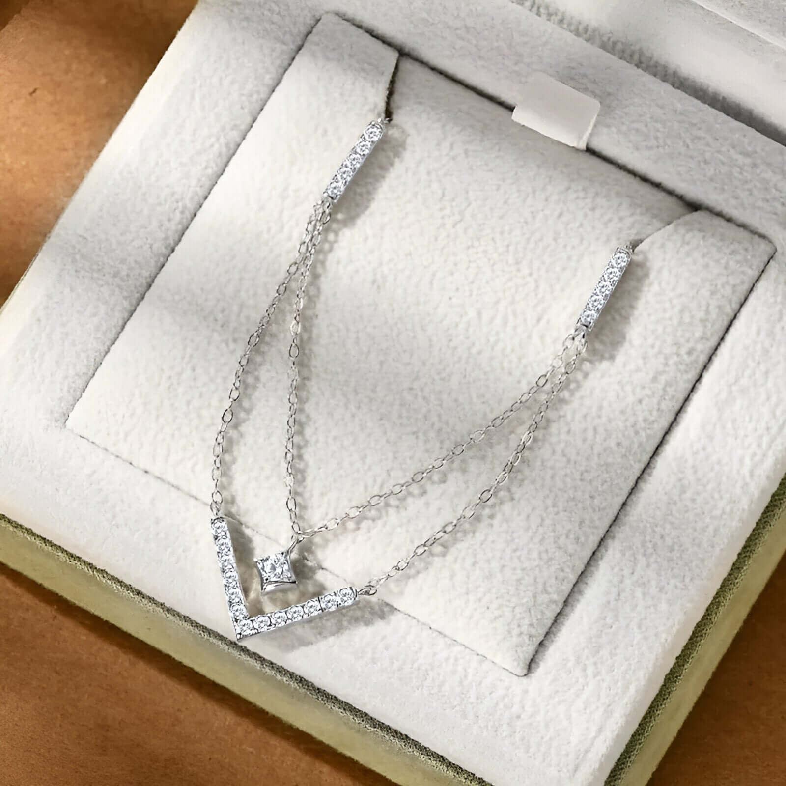 Collier pendentif V maille double en argent 925 plaqué or blanc et moissanites rangé dans son écrin vue du dessus.