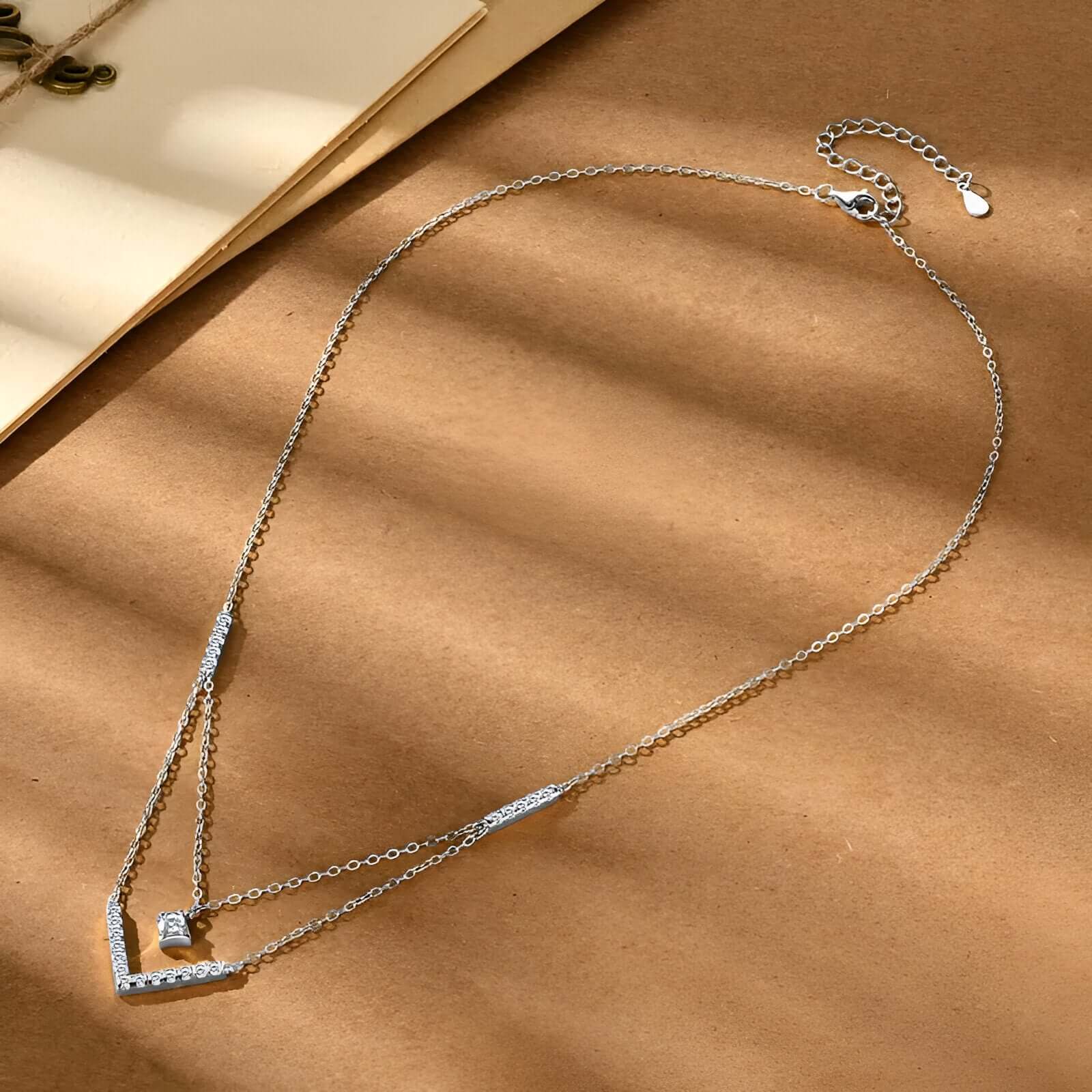 Collier pendentif V maille double en argent 925 plaqué or blanc discret et moissanites à plat vue de côté.