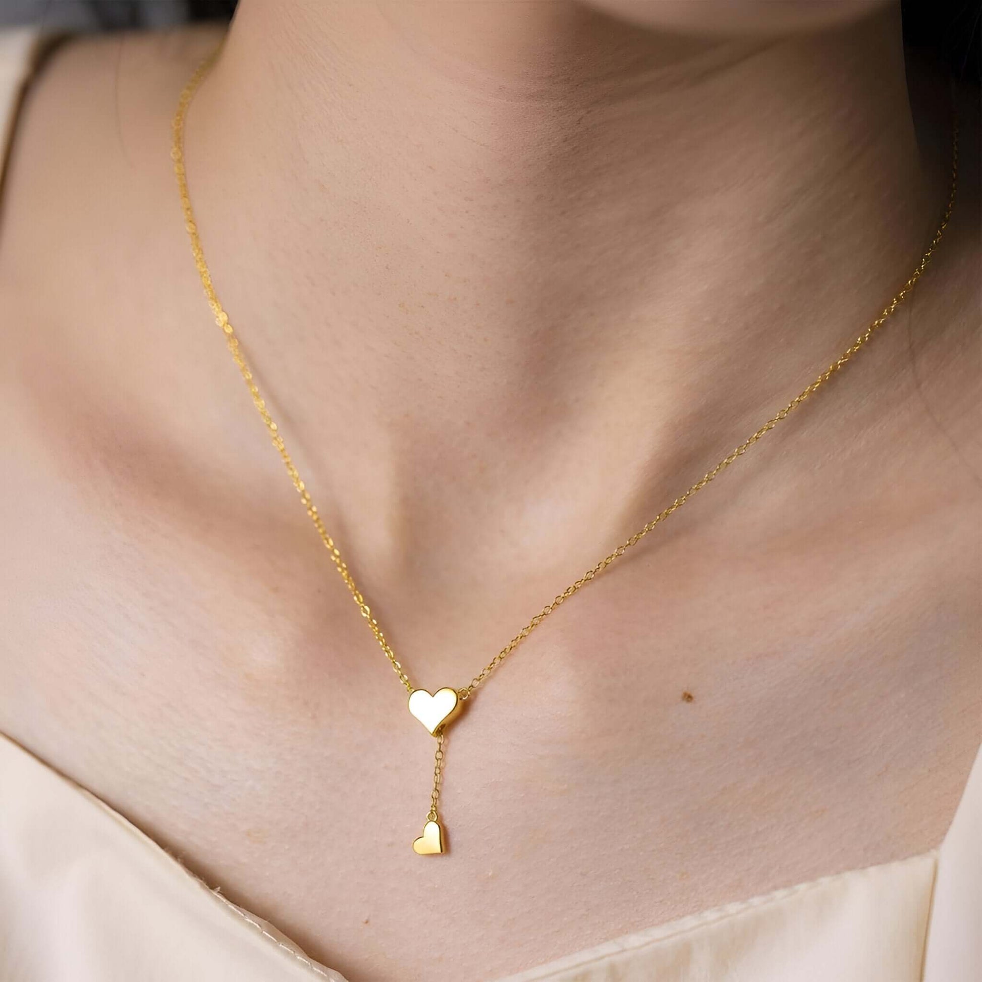 Collier sautoir cœur amovible en argent plaqué or jaune porté au cou d'une femme.