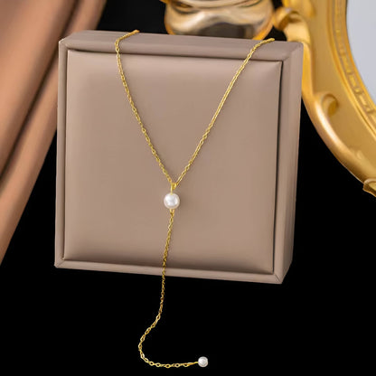 Collier sautoir perle en acier inoxydable plaqué or jaune orné de perles sur un écrin.