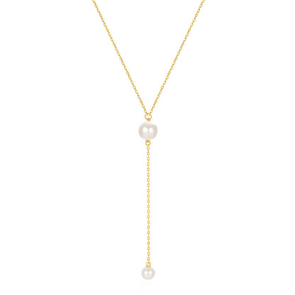 Collier sautoir perle en acier inoxydable plaqué or jaune orné de perles sur fond blanc.