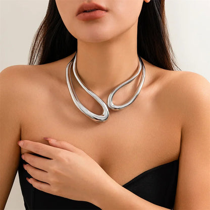 Collier torque goutte d'eau en or blanc porté au cou d'une femme.