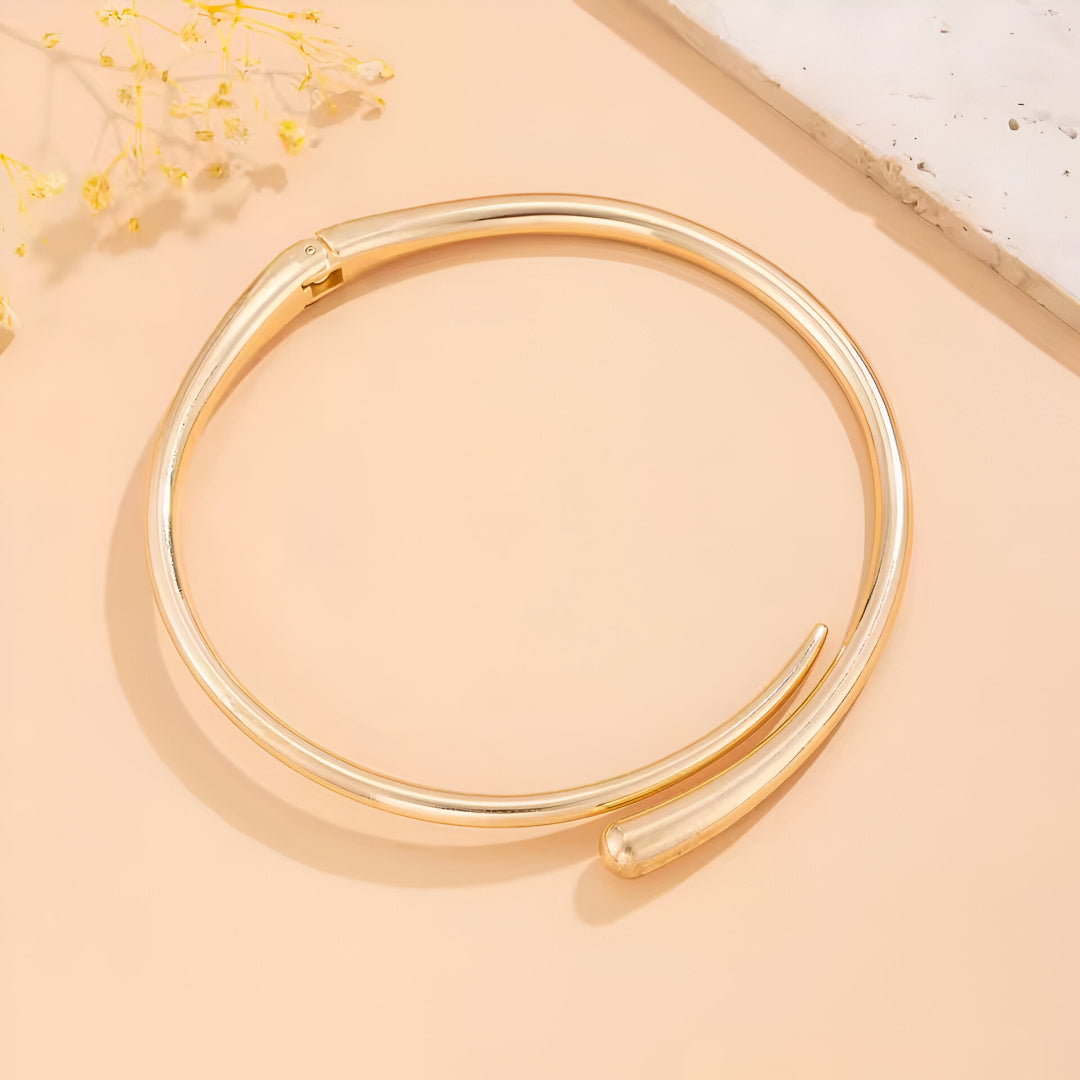 Collier torque goutte d'eau en or jaune à plat.