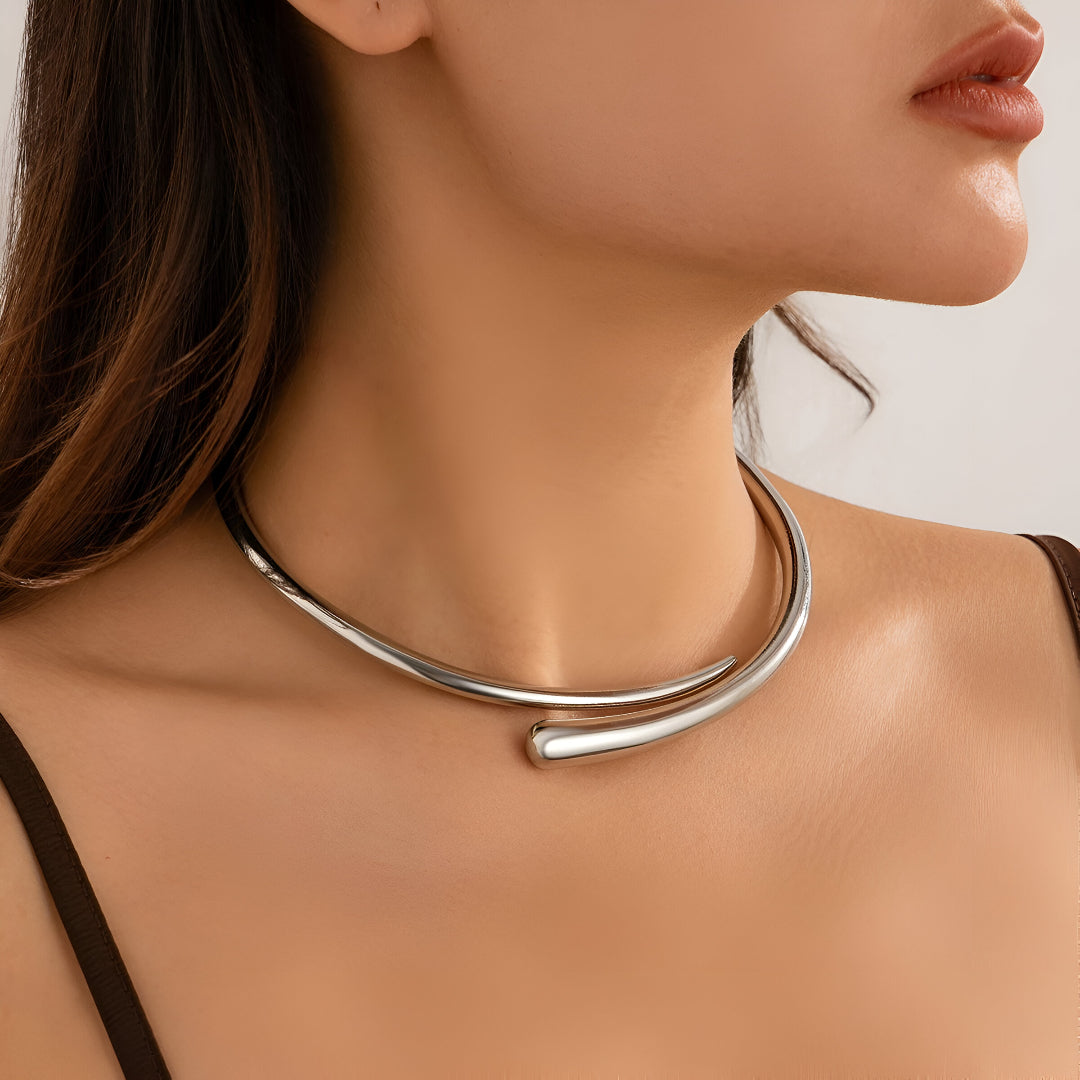 Collier torque goutte d'eau en platine porté au cou d'une femme vue de côté.