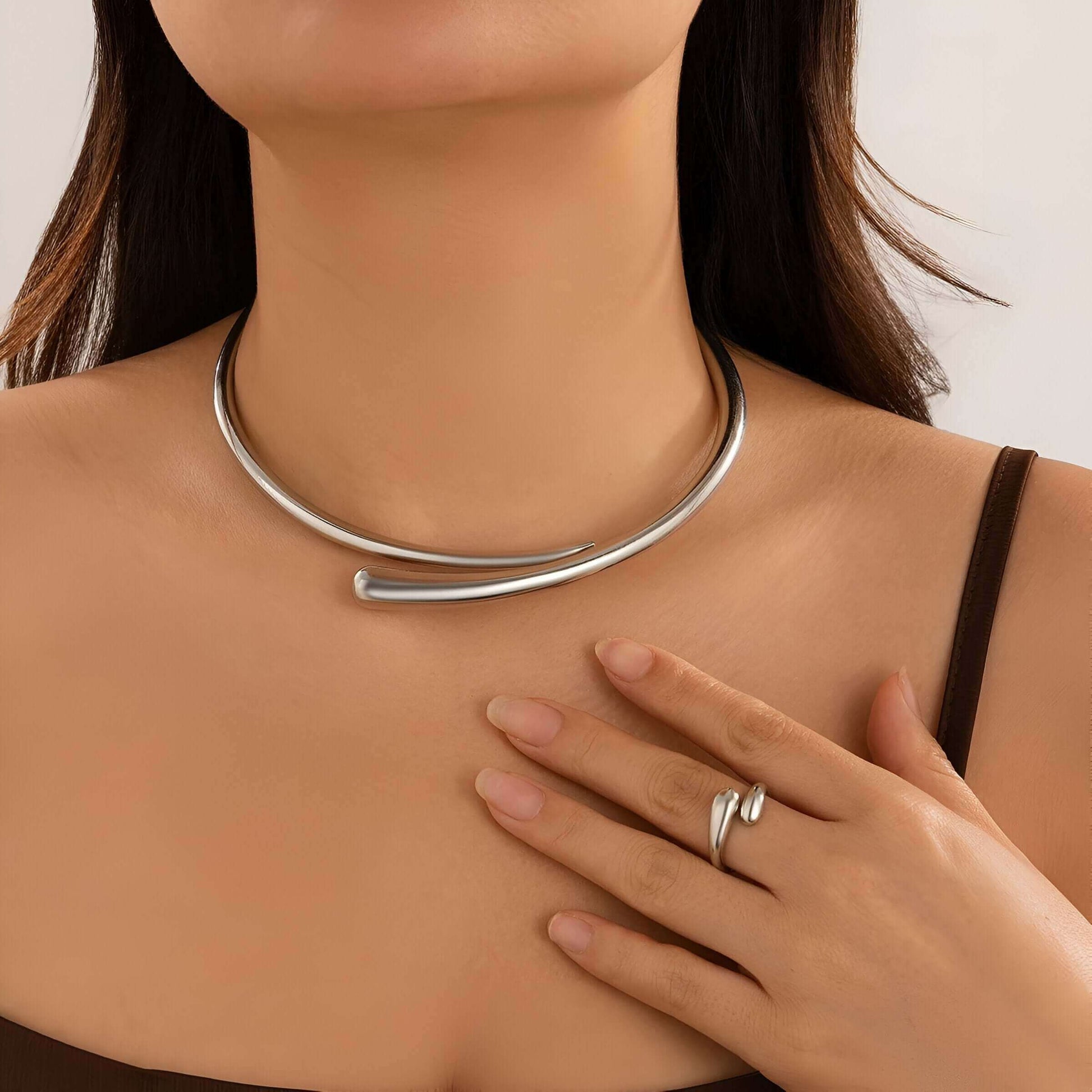 Collier torque goutte d'eau en platine porté au cou d'une femme vue de face.