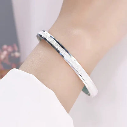 Jonc fin granulé en argent sterling 925 porté au poignet d'une femme.