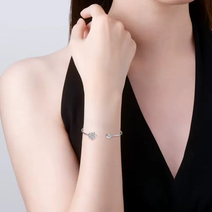 Bracelet jonc fleur Véraë en argent plaqué or blanc et moissanites serties clos porté au poignet d'une femme vue de face.