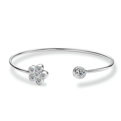 Bracelet jonc fleur Véraë en argent plaqué or blanc et moissanites serties clos sur fond blanc.