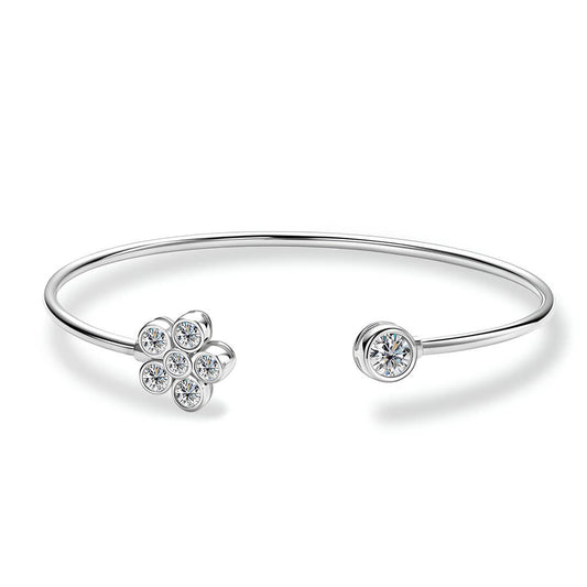 Bracelet jonc fleur Véraë en argent plaqué or blanc et moissanites serties clos sur fond blanc.