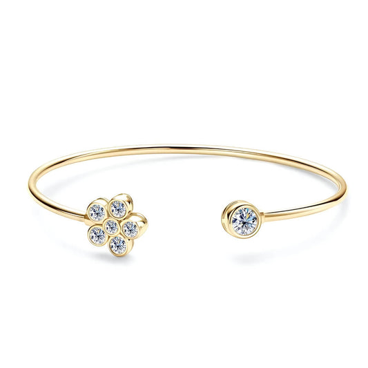 Bracelet jonc floral en argent 925 plaqué or jaune et diamants en moissanite sur fond blanc. 
