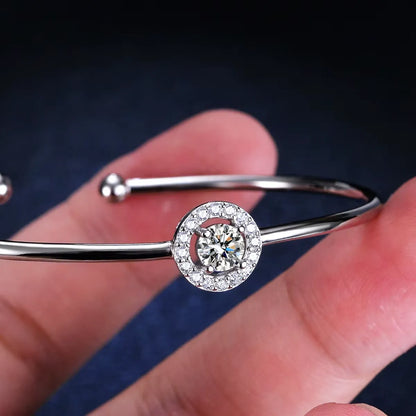 Jonc halo solitaire en argent 925 plaqué or blanc et diamants en moissanite entre les doigts d'une femme vue de proche.