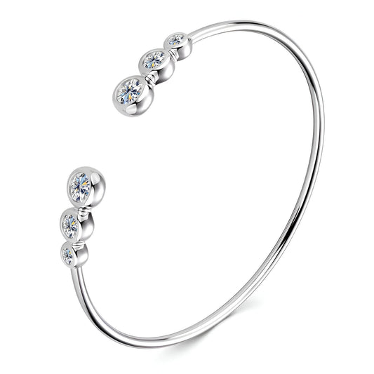 Bracelet jonc serti clos nathy en argent 925 plaqué or blanc et moissanites sur fond blanc.