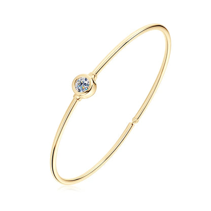 Jonc solitaire fin en argent 925 plaqué or jaune et diamant serti clos sur fond blanc.