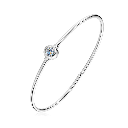 Bracelet jonc solitaire myel en argent plaqué or blanc et moissanite serti clos sur fond blanc.