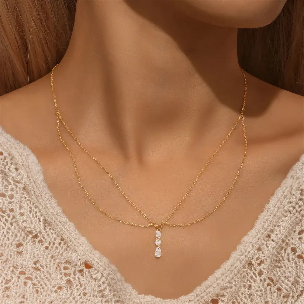 Multi-chaînes en argent 925 plaqué or jaune et pendentif d'oxydes de zirconium scintillants porté au cou d'une femme vue de face.