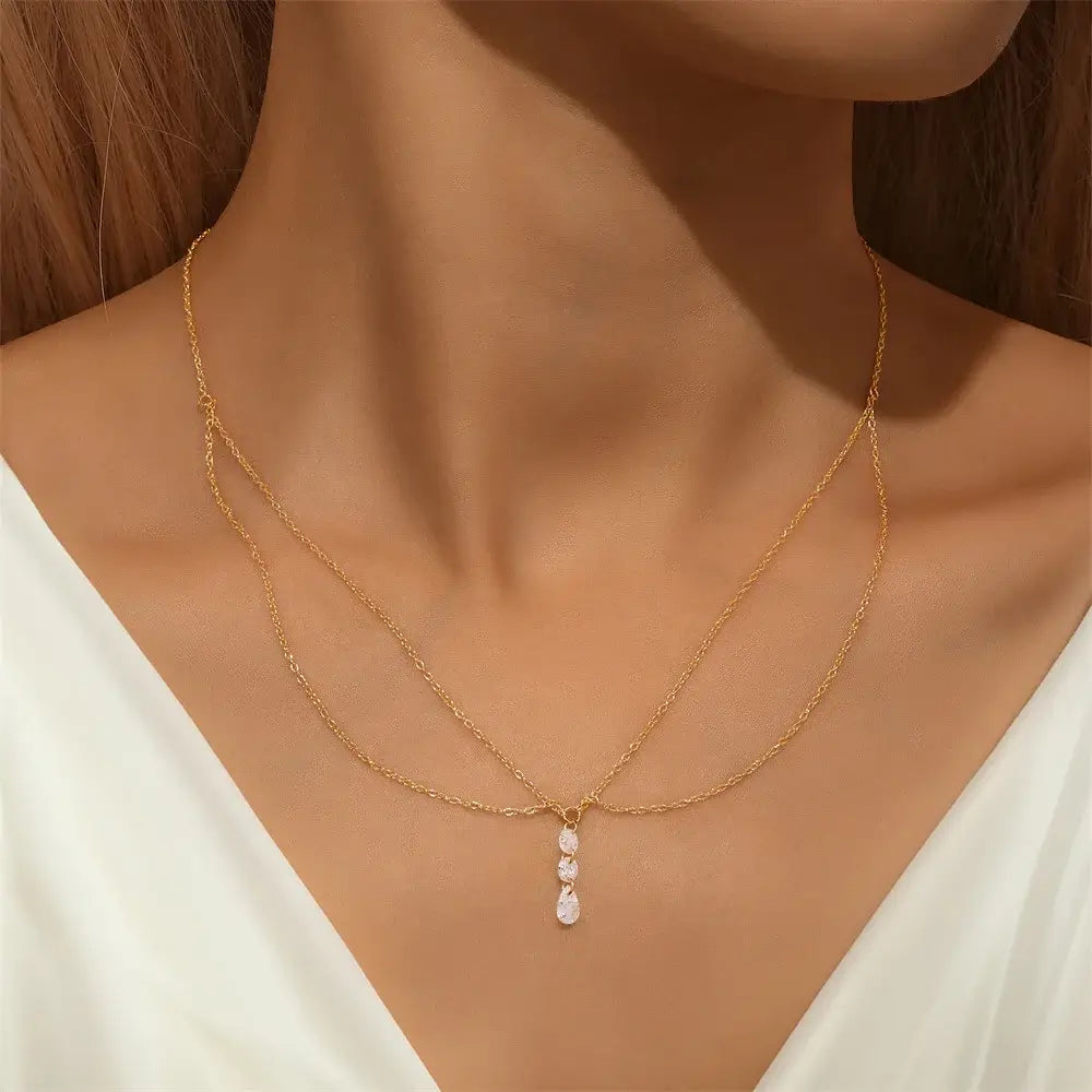 Collier multi-chaînes en argent 925 plaqué or jaune et pendentif d'oxydes de zirconium porté au cou d'une femme.