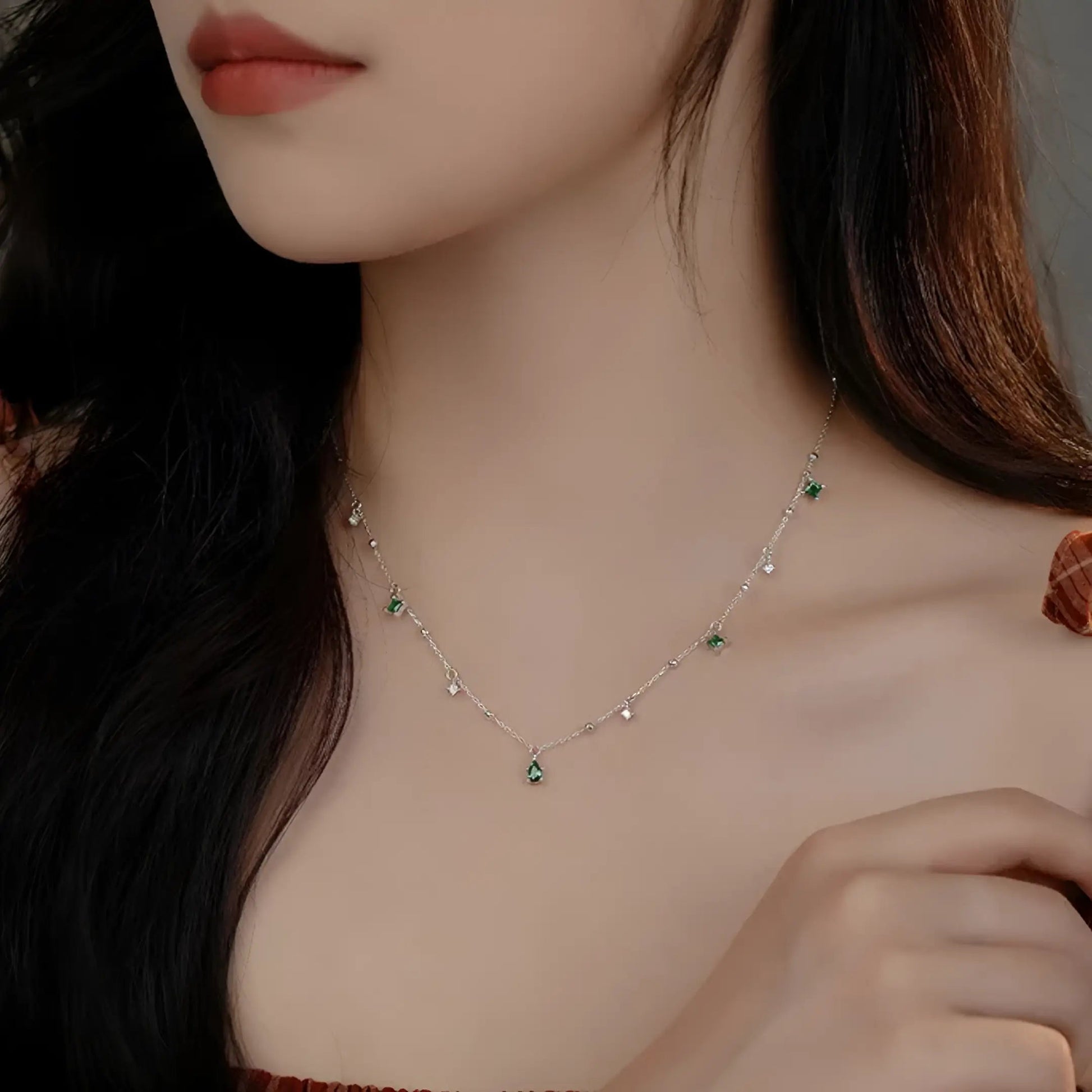 Pendentif à breloques en or blanc et diamants naturels porté au cou d'une femme vue de face.