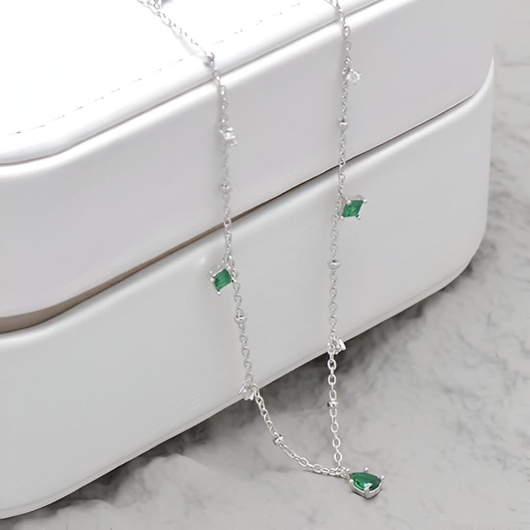 Pendentif à breloques en or blanc et diamants naturels posé sur un écrin.