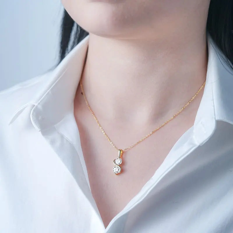 Pendentif arqué serti invisible en argent 925 plaqué or jaune et duo de diamants éclatants porté au cou d'une femme.