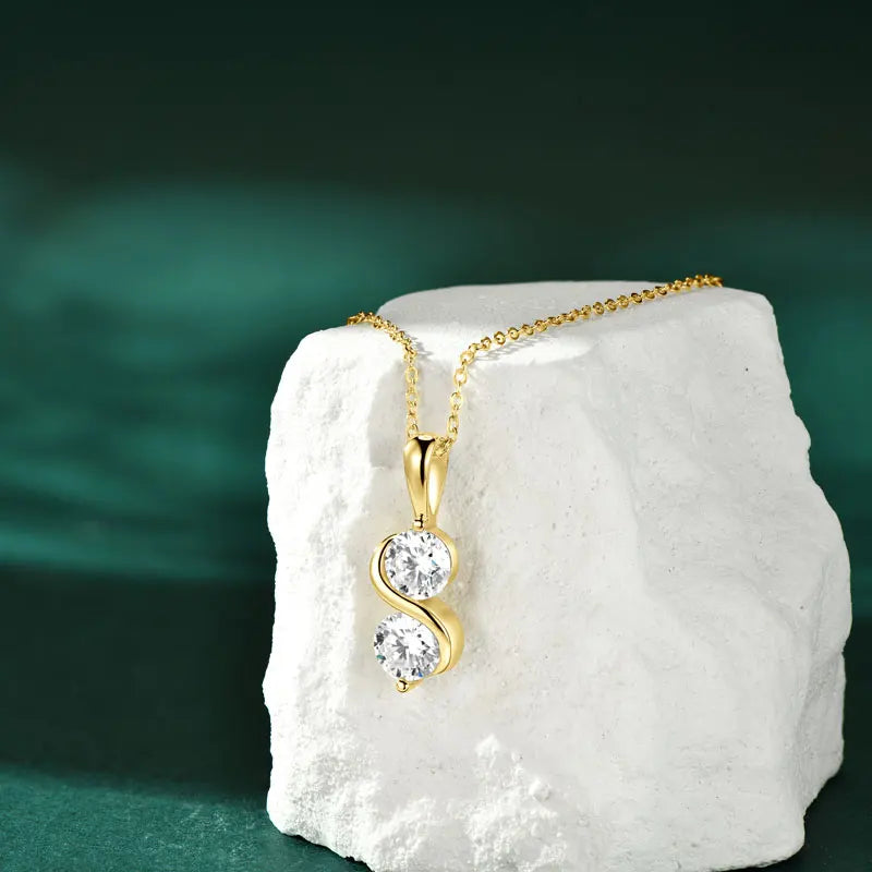 Pendentif arqué serti invisible en argent 925 plaqué or jaune et duo de diamants posé sur une pierre blanche.
