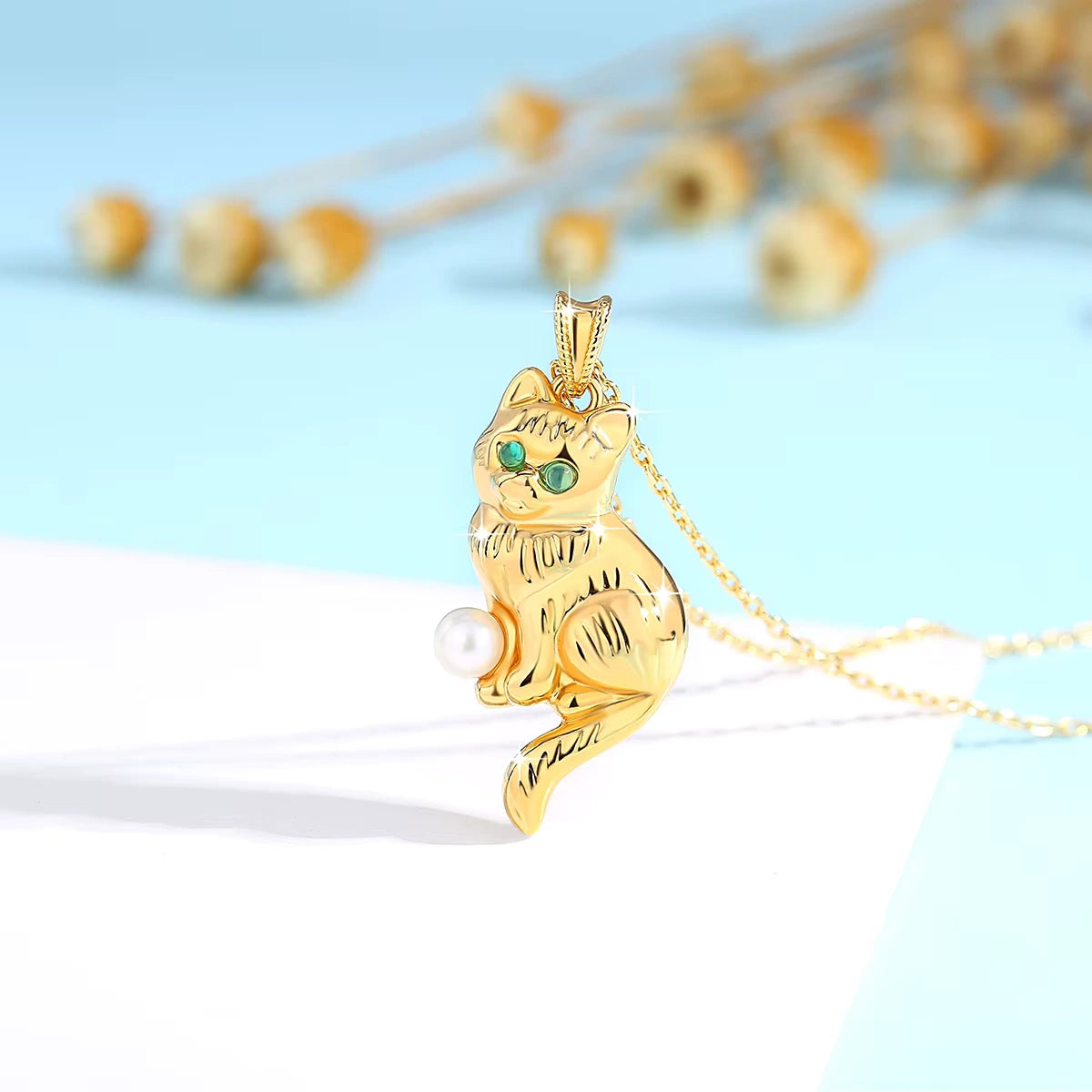 Pendentif chat Cathy en or jaune 18K serti d'une perle ronde et de péridots ronds scintillants debout.