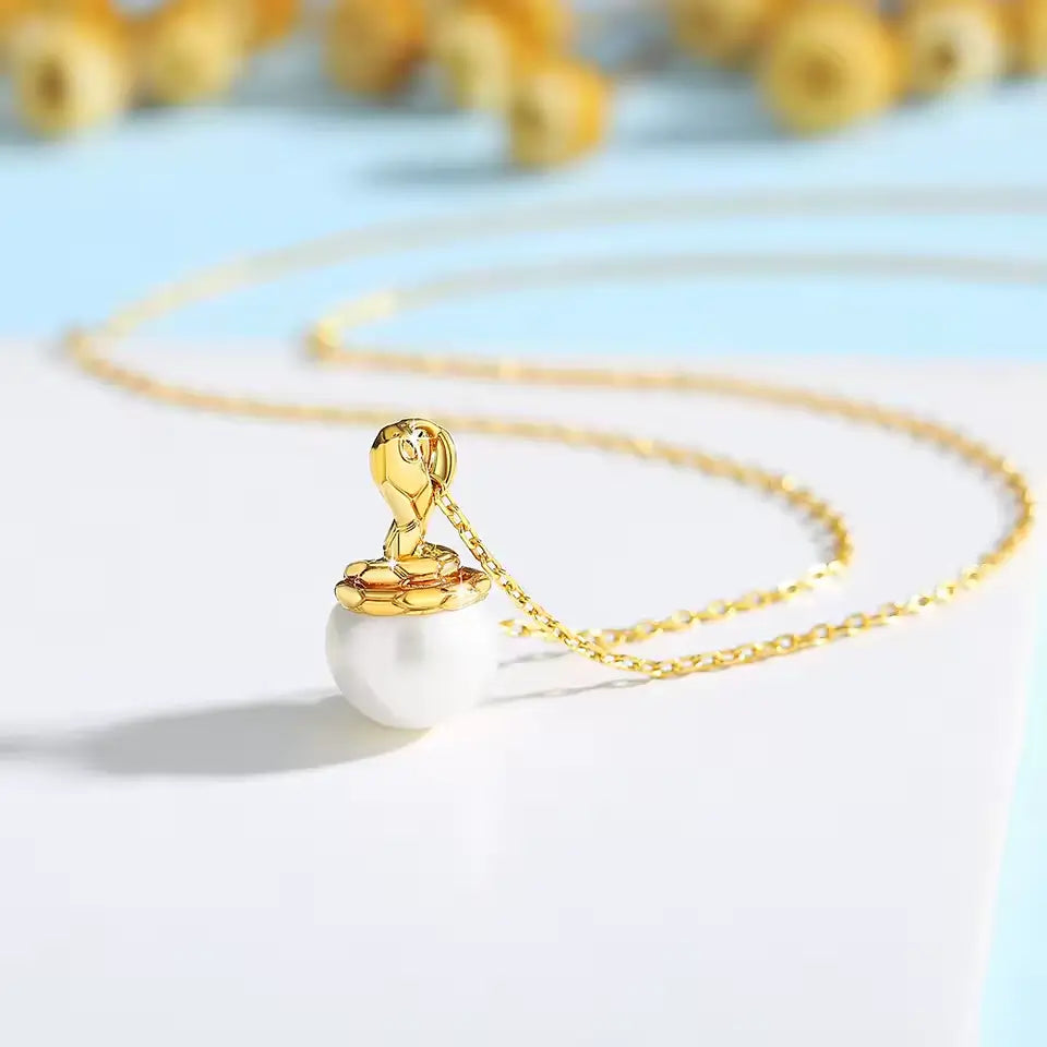 Pendentif cobra doré Sarah en or jaune 18K étincelant et perle naturelle nacrée vue de côté.