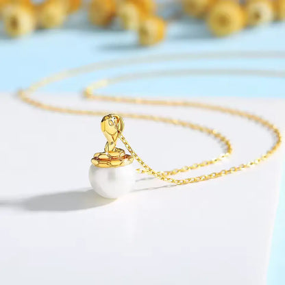 Pendentif cobra doré Sarah en or jaune 18K étincelant et perle naturelle nacrée vue de côté.