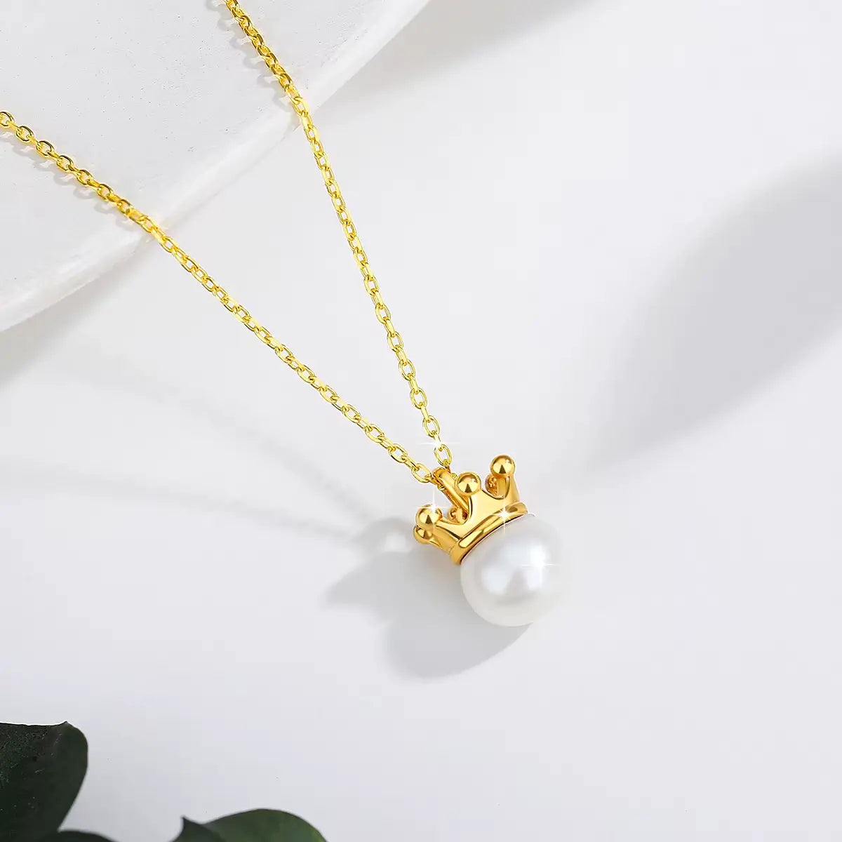 Pendentif couronne du roi Louis en or jaune 18K lumineux et perle naturelle posé.