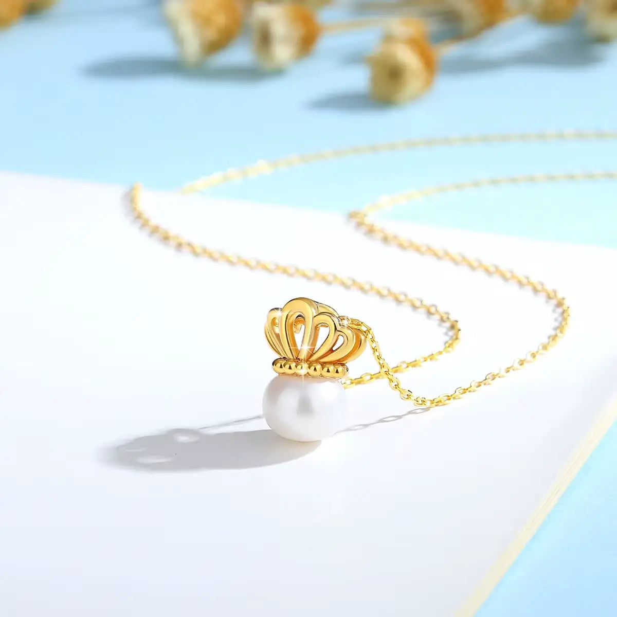 Pendentif couronne de reine en or jaune et perle ovale debout.