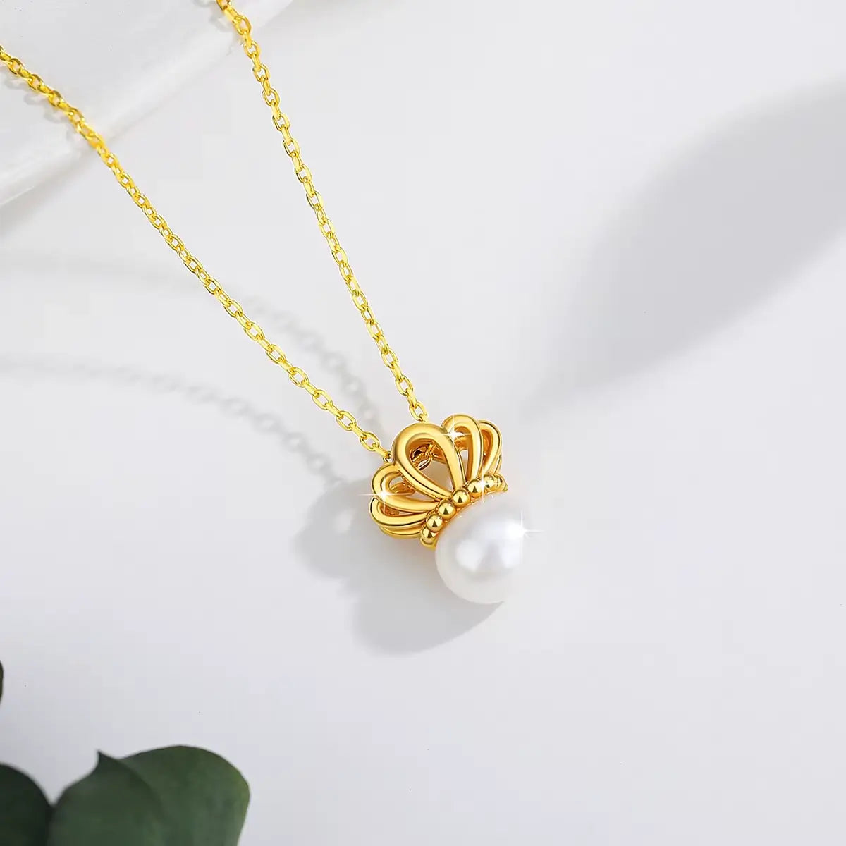 Pendentif couronne de reine en or jaune et perle ovale vue du dessus.