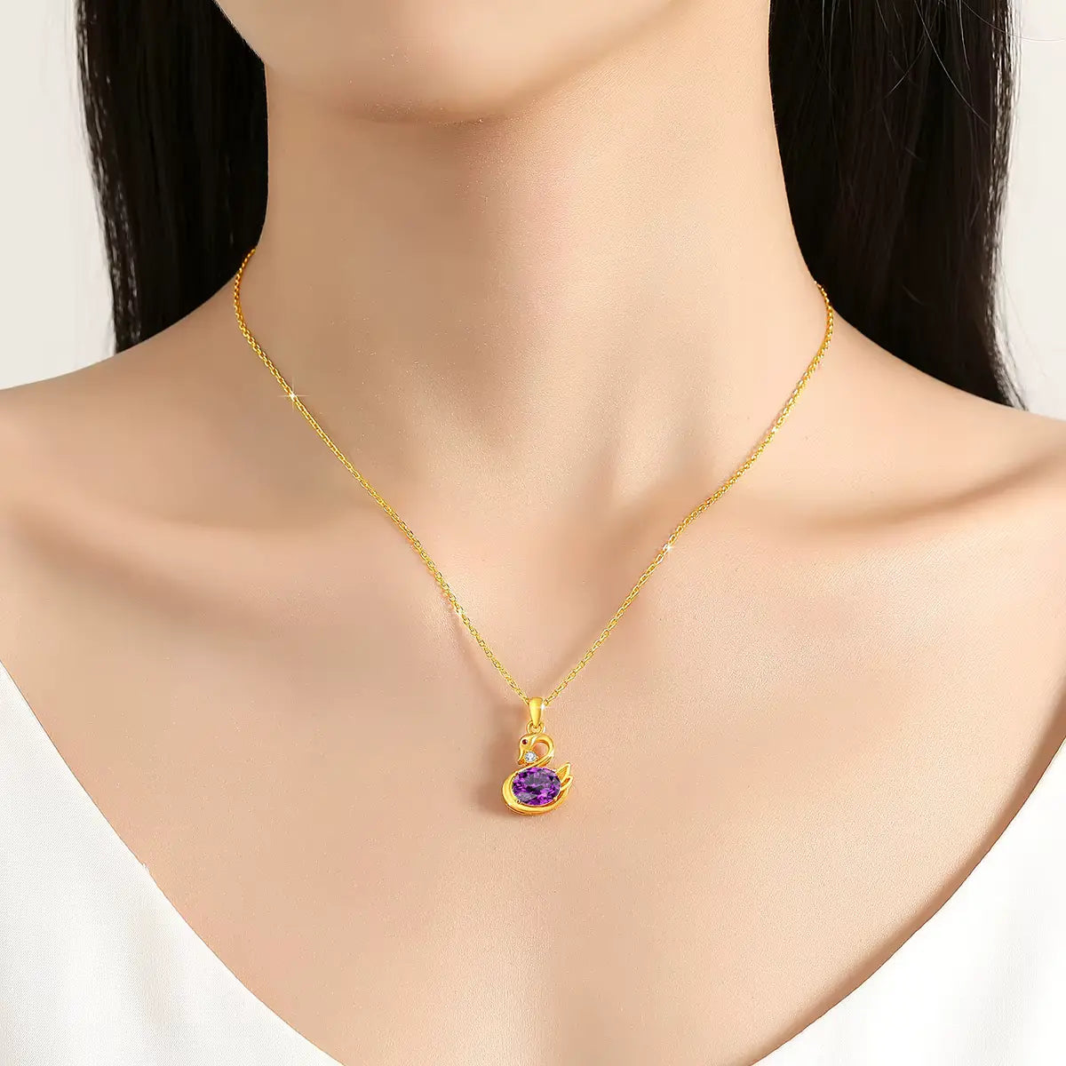 Pendentif cygne améthyste impérial Livie en or jaune 18K monté d'un diamant et d'un rubis porté au cou d'une femme vue de face.