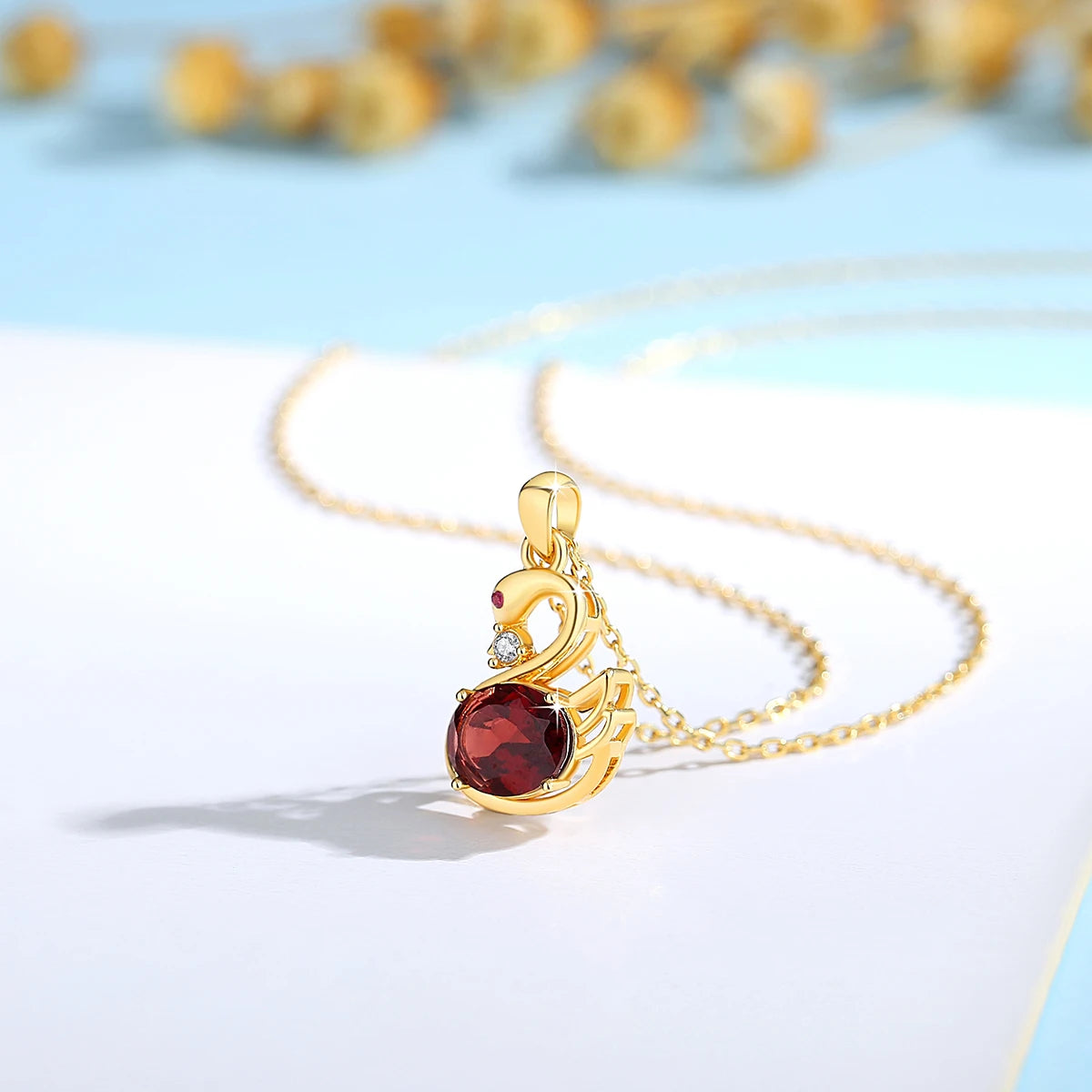 Pendentif cygne grenat romantique en or jaune 18K raffiné serti d'un diamant et d'un rubis vue de côté.