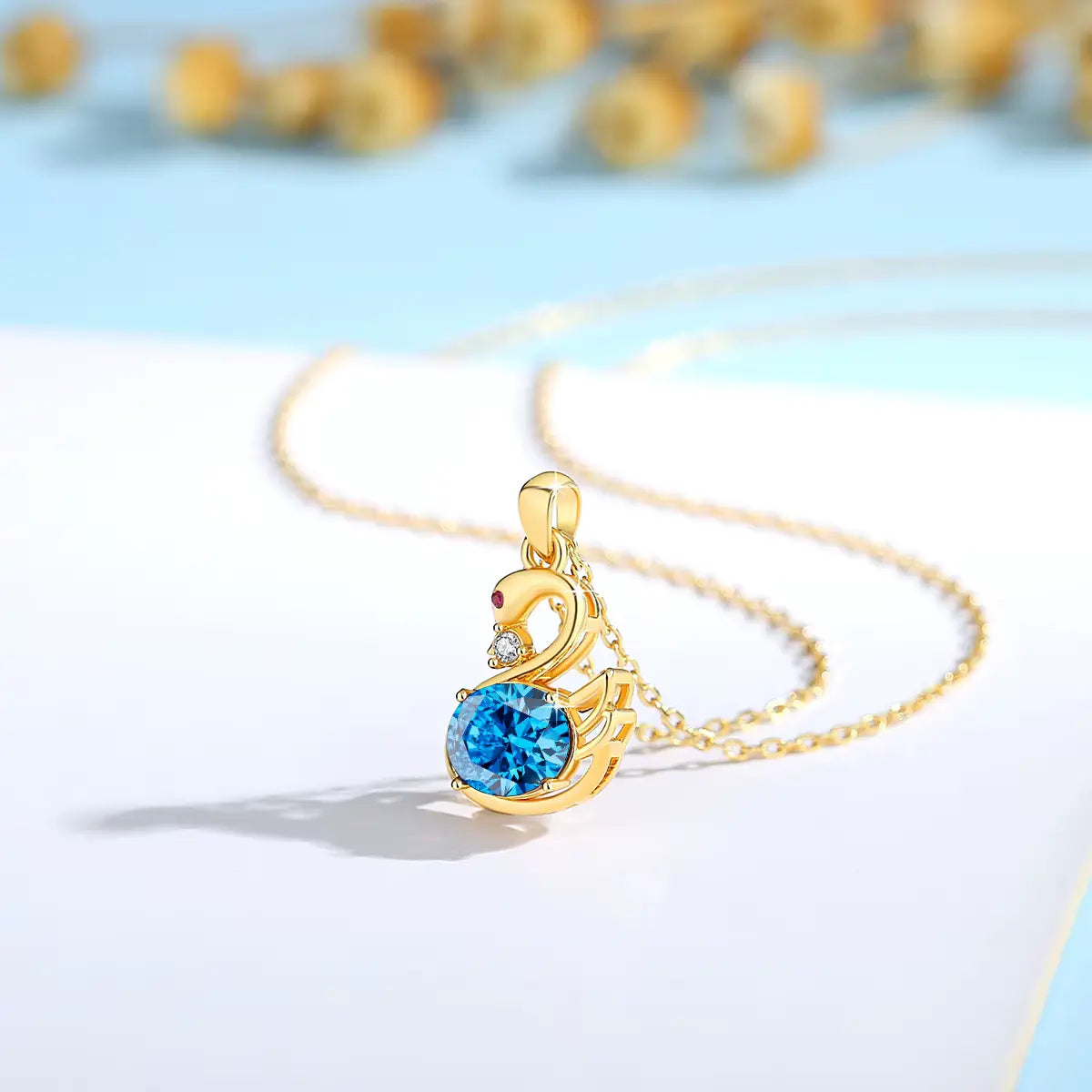 Pendentif cygne topaze radieuse en or jaune 18K orné d'un rubis éclatant et d'un diamant vue de côté.